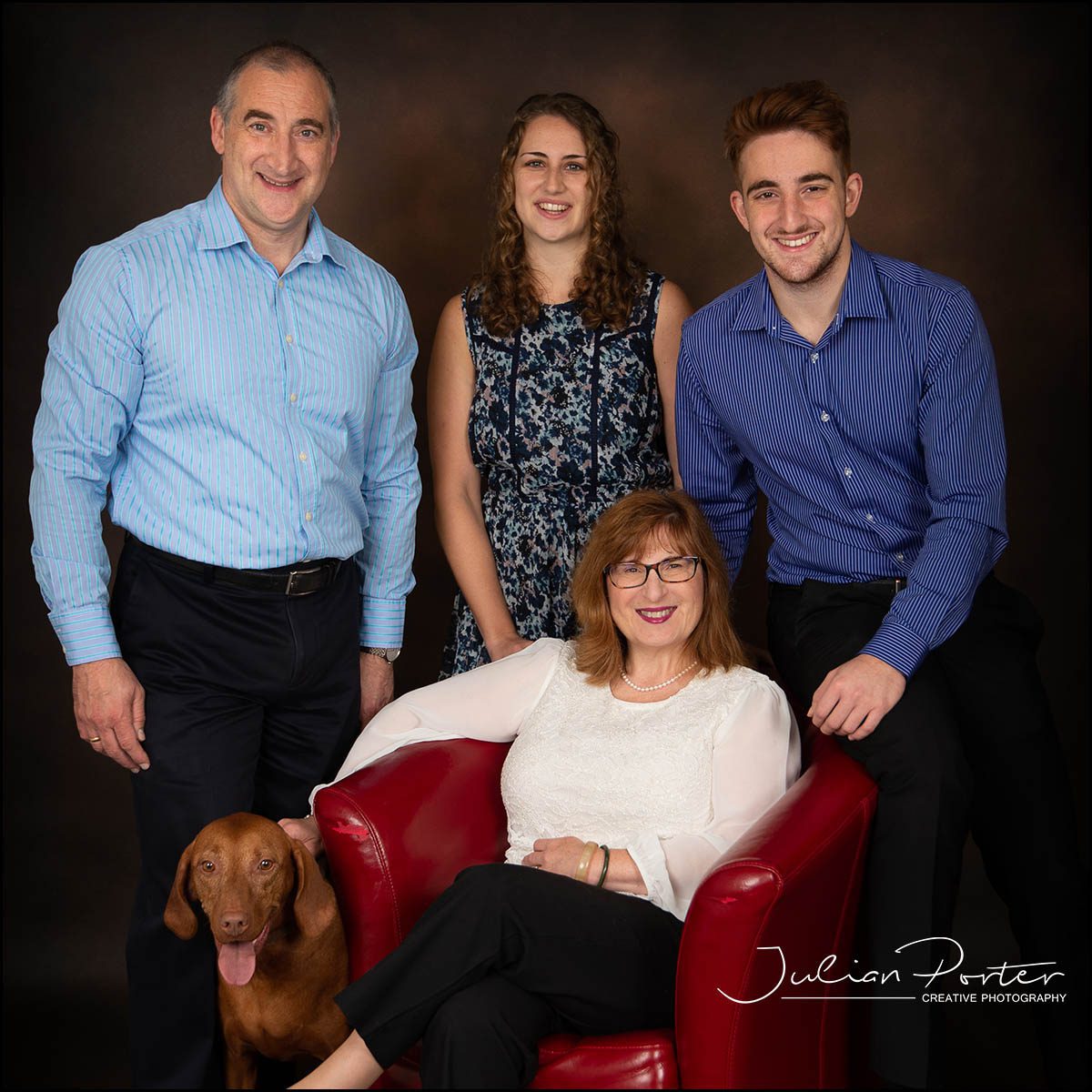Family sitting on a red chair with dog